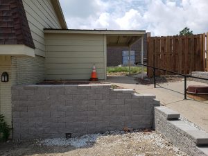 Stone retaining wall installation is progress by Norwalk Seasonal Services