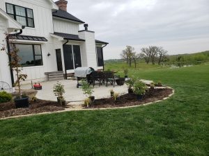 Sweeping Flower Bed filled with mulch lined with limestone edging with flagstone steps and by Norwalk Seasonal - Des Moines, Iowa
