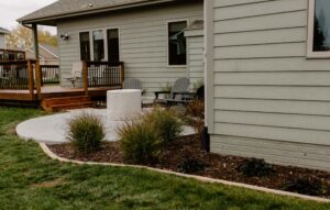 Backyard Limestone edged Mulch Garden bed leading to a poured concrete patio with covered firepit Norwalk Seasonal - Des Moines, Iowa