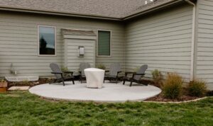 Poured concrete patio with a firepit surrounded on the backside by a limestone edged mulch garden bed. Norwalk Seasonal - Des Moines, Iowa