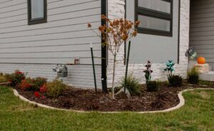 Mulch garden bed with plants lined with limestone edging on the corner of House Mulch Trees and Plants Norwalk Seasonal - Des Moines, Iowa