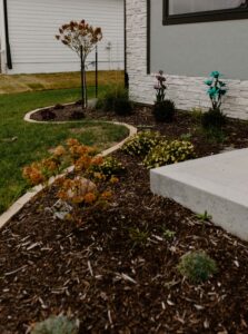 Mulch garden bed lined with limestone edgers with plants and limestone edging around Utilities Norwalk Seasonal - Des Moines, Iowa also pictured a poured concrete step