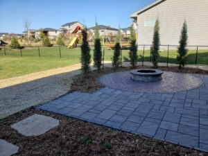 Stone Walkway and Firepit with Patio Unilock Pavers used for the patios Norwalk Seasonal - Des Moines, Iowa Also pictured is a much garden with trees planted around the outside circumference of the rounded portion of the patio.
