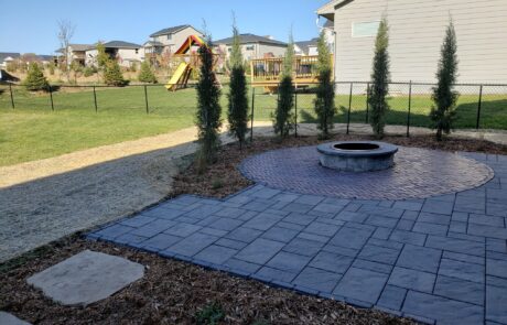 Stone Walkway and Firepit with Patio Unilock Pavers used for the patios Norwalk Seasonal - Des Moines, Iowa Also pictured is a much garden with trees planted around the outside circumference of the rounded portion of the patio.