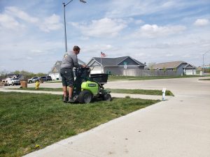 Yard seed performed by Norwalk Seasonal - Des Moines, Iowa - Pictured is a man on a green commercial fertilizing buggy