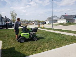 Yard Seeding done by Norwalk Seasonal - Des Moines, Iowa Pictured is a NSS employee on a fertilizing buggy, fertilizing a lawn.