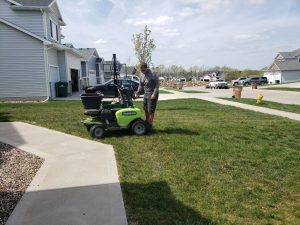 Yard Seeding done by Norwalk Seasonal - Des Moines, Iowa. Pictured is a man on a green commercial fertilizing buggy