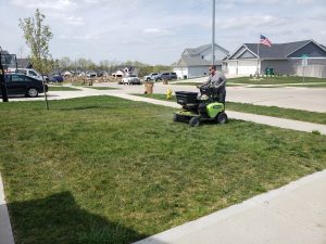 Yard seed spreading done by Norwalk Seasonal - Des Moines, Iowa. Pictured is a man on a green commercial fertilizing buggy