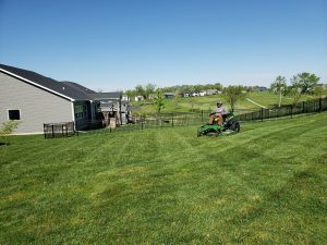 Yard Maintenance from Norwalk Seasonal - Des Moines, Iowa - A Norwalk Seasonal Services Employee is pictured on a green commercial riding lawn mower.