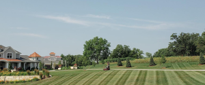 A large estate with a large lawn bring mowed with perfect lines by a member of the Norwalk Seasonal Services team