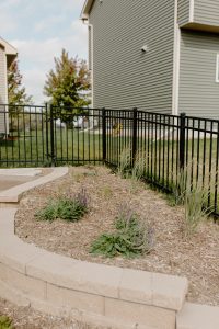 Retaining wall with a raised garden bed above filled with greenery and mulch