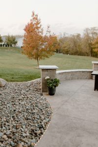 Close up of a seating retaining wall combo surrounded by a rock garden. Also pictured is the lighting around the textured poured concrete patio