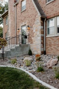 Close up of the rock garden near the base of a 2 story brick house