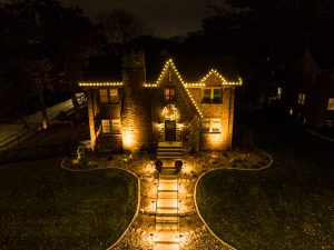 2 story house lit up in white Christmas lights with a lighted walkway