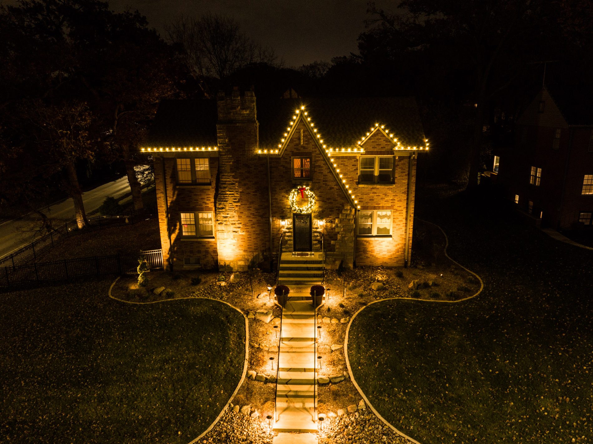 2 story house lit up in white Christmas lights with a lighted walkway